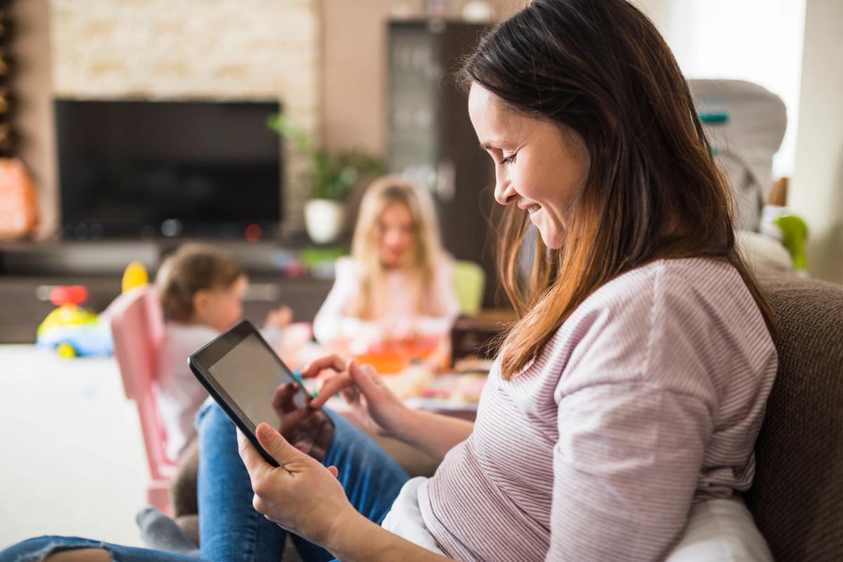 Happy calm mother using a digital planner on a tablet at home